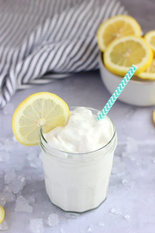 frosted lemonade in glass on table with straw and lemon slice