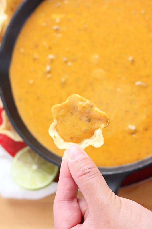 queso dip on chip above skillet