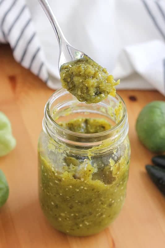 green salsa held on a spoon over a mason jar
