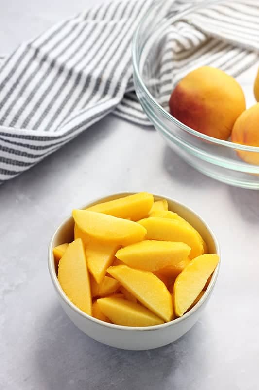 peaches sliced in bowl on top of table.
