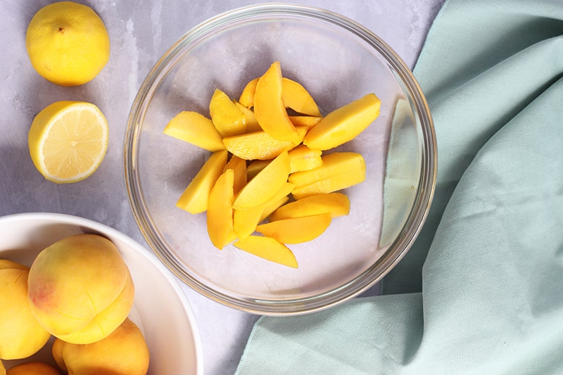 peeled and sliced peaches in glass bowl