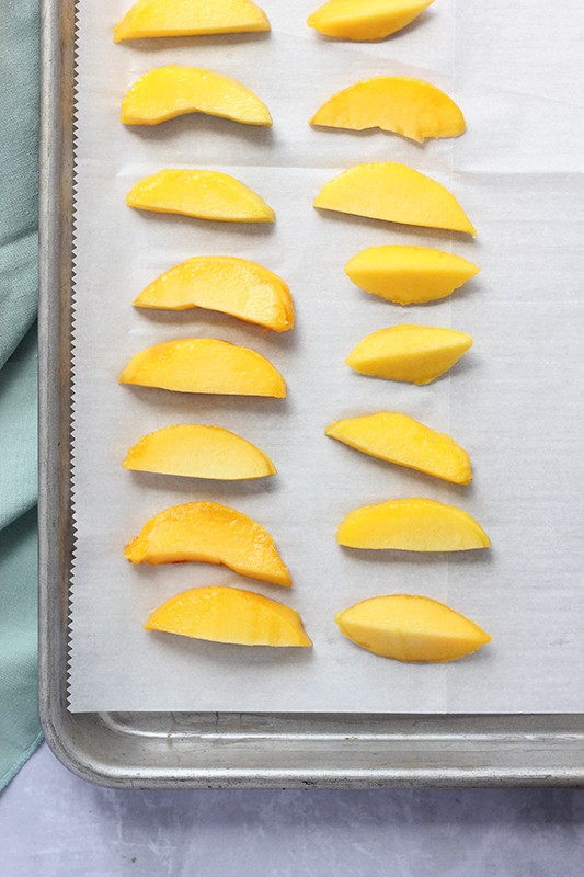 slices of peaches in a single layer on parchment paper