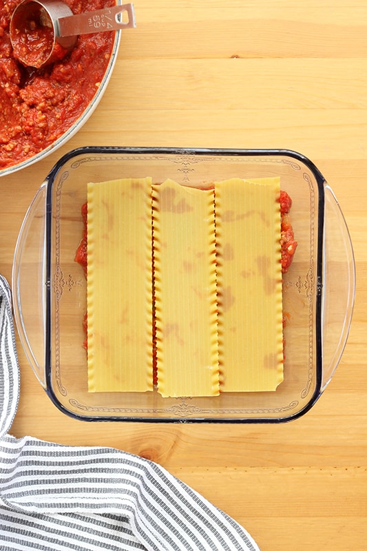 lasagna noodles layered in pan over sauce