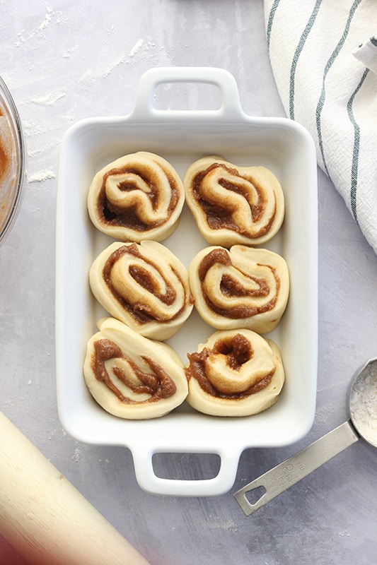 Raw cinnamon rolls ready to be baked in a white pan