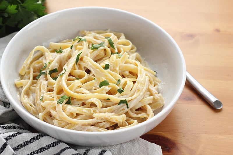 bowl of fettuccine pasta in a shallow white bowl with a white cheese sauce