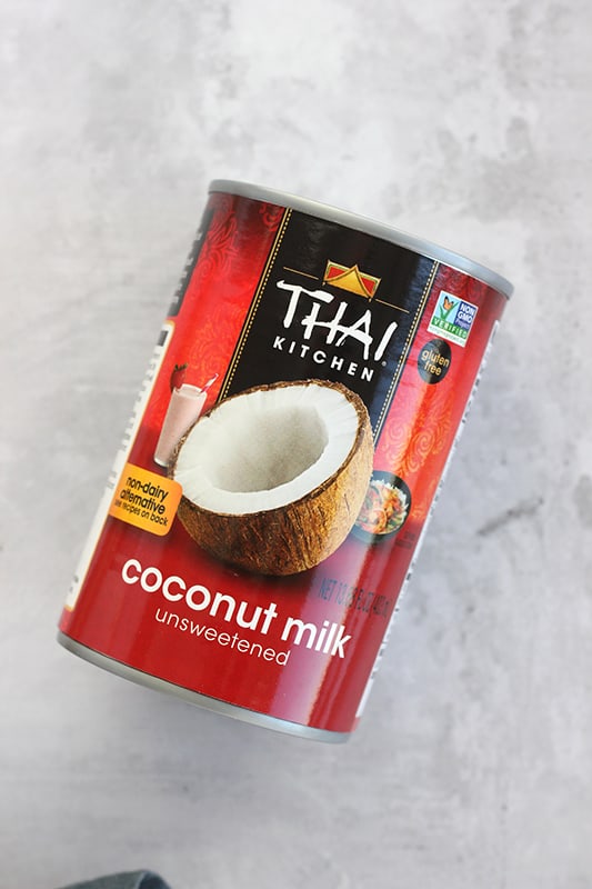 can of thai kitchen unsweetened coconut milk laying on a concrete colored backdrop