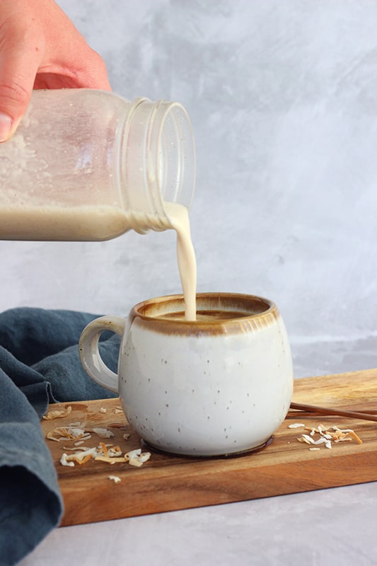 how to make a coconut milk latte- coconut milk being poured from mason jar into mug