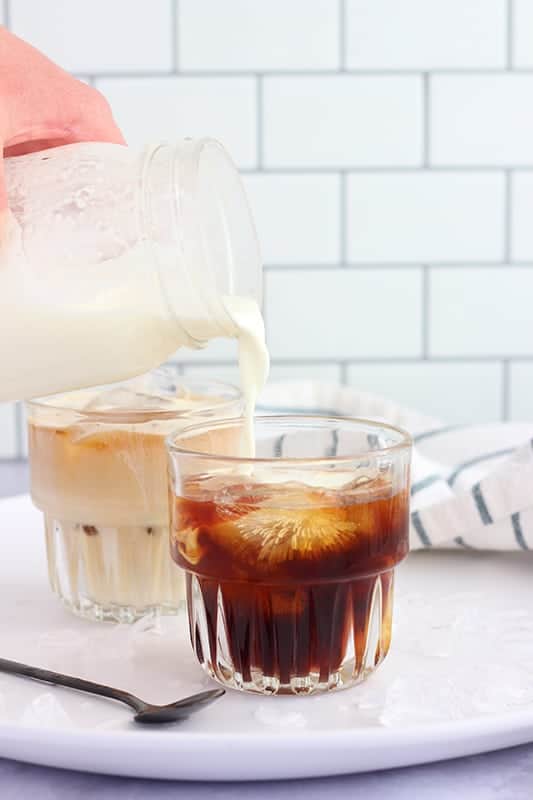 sweet cream being poured into cold brew coffee