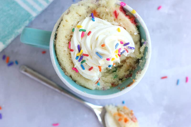 mug cake with vanilla frosting and rainbow sprinkles