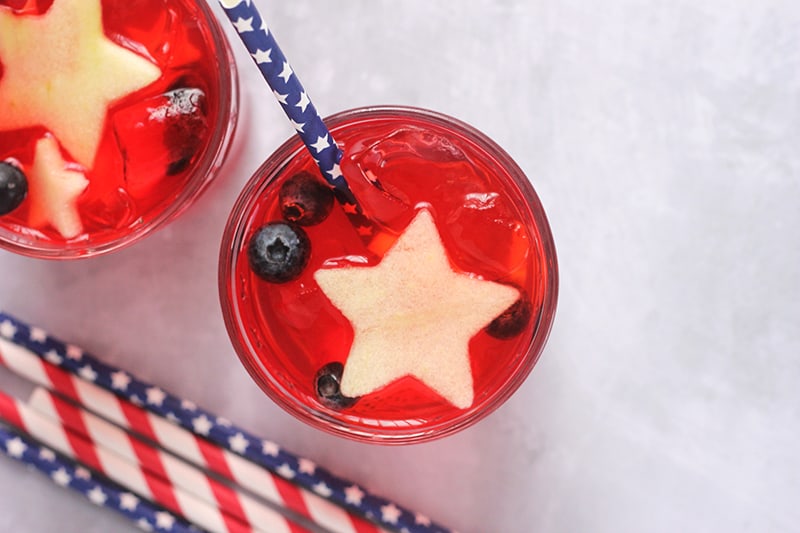 glass filled with a red punch and topped with fresh blueberries and apples chopped into stars