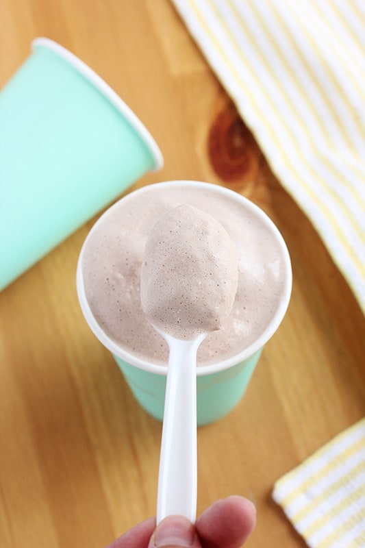 bite of chocolate frosty on a plastic spoon over a cup
