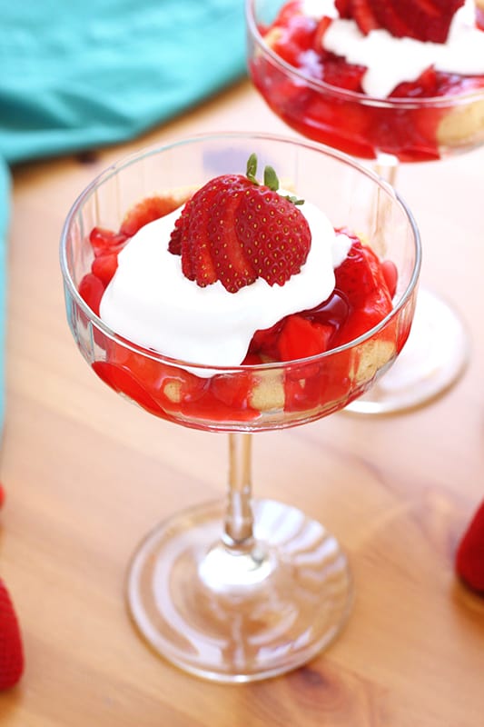 tall martini glass filled with strawberry cake and whipped cream