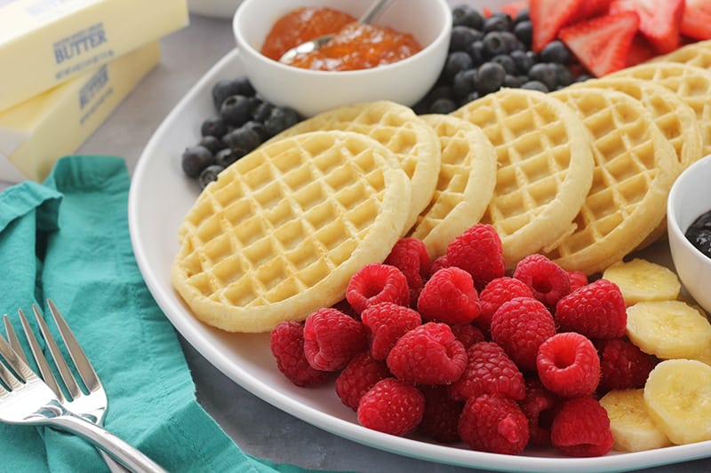 waffles on a tray with fresh fruit and spreads