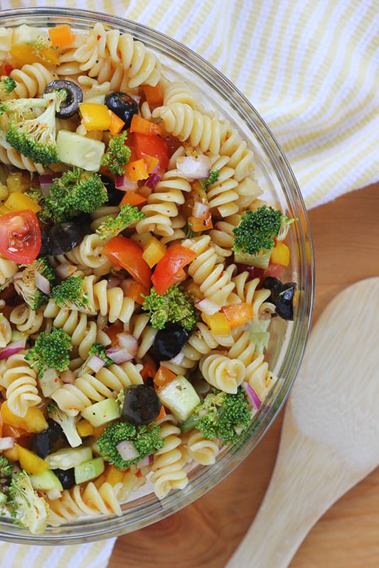 close up image of a glass mixing bowl filled with pasta salad 