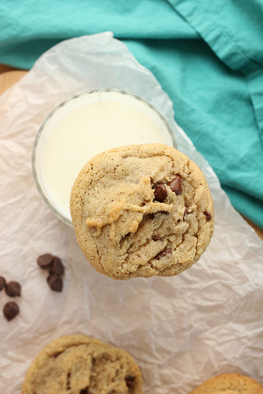 Browned butter chocolate chip cookie balancing on a glass of milk