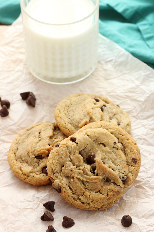 stack of browned butter cookies on parchment paper with extra chocolate chips