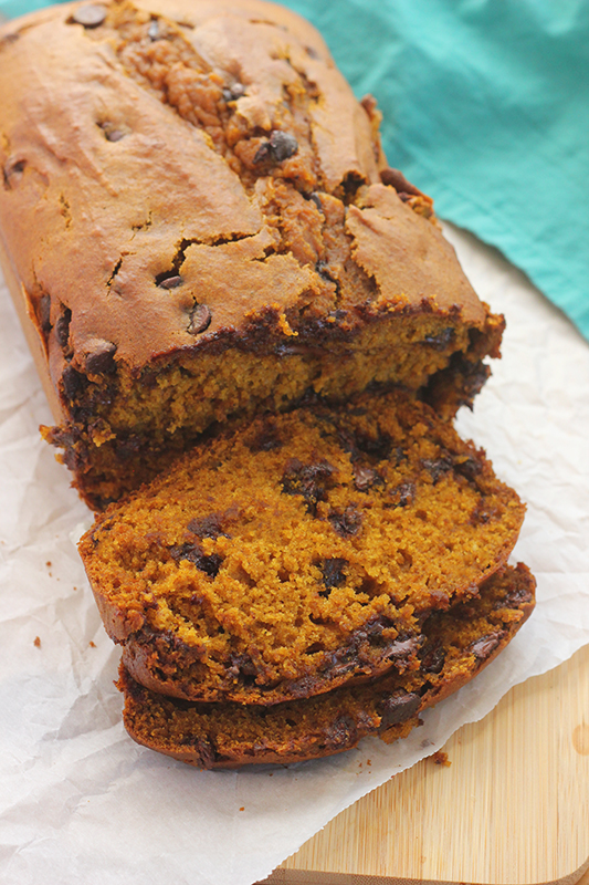 Warm loaf of pumpkin bread with chocolate chips on a piece of parchment paper