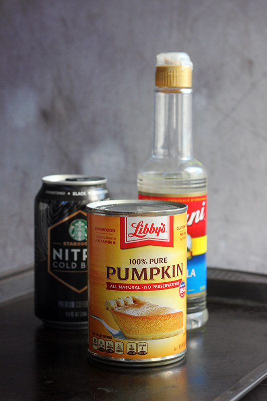 pumpkin puree in a can, canned coffee, and vanilla syrup on a black baking tray