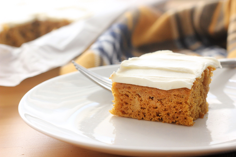 pumpkin cake topped with cream cheese frosting sitting on a white plate
