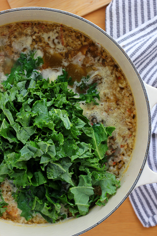 Pot of soup topped with fresh kale