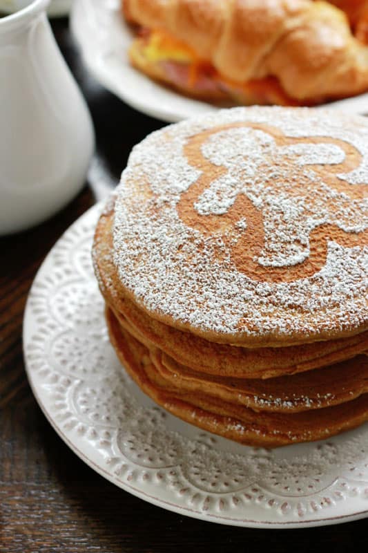side view of a stack of pancakes on a white trimmed plate