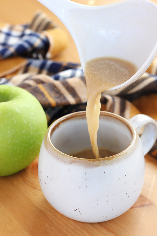 ladle pouring apple cider into a mug
