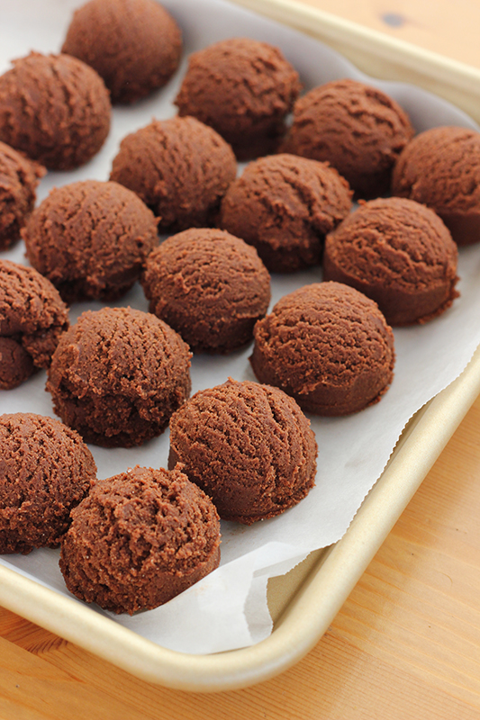 chocolate cookie dough rolled into balls on a parchment lined baking tray