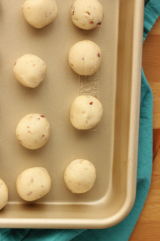 snowball cookie dough rolled onto a baking tray
