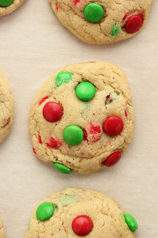 christmas m&m cookies cooling on a piece of white parchment