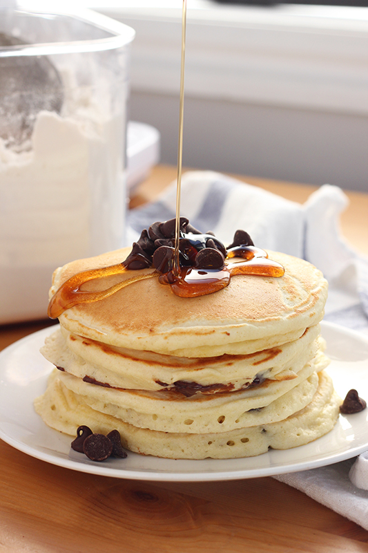 syrup being drizzled onto a stack of pancakes