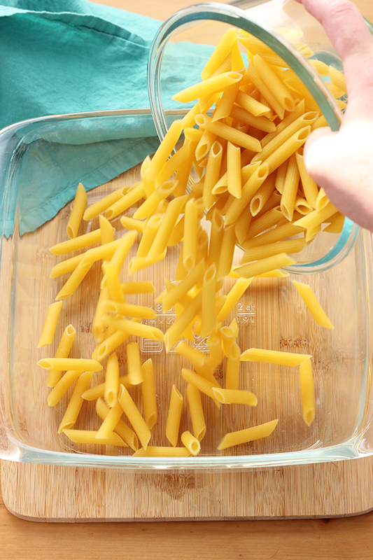 dry pasta pouring into a baking dish