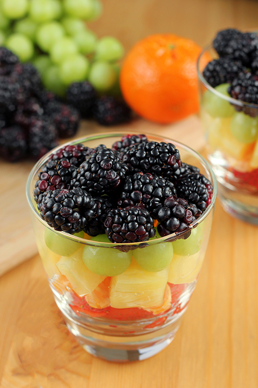 close up of a cup of fruit with blackberries, grapes, pineapple, oranges, and strawberries