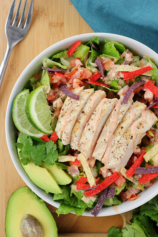 top down image of a southwest style salad with grilled chicken in a white bowl