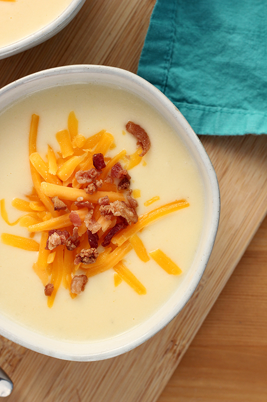 top down image of a white bowl filled with soup and toped with shredded cheese and bacon pieces 