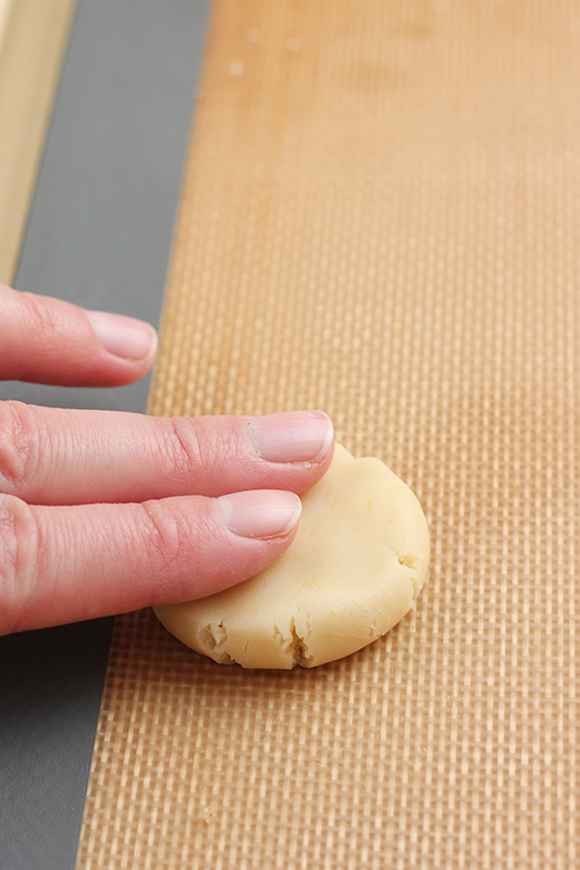 cookie dough being pressed down by two fingers
