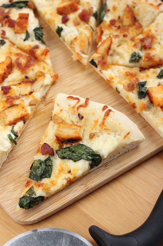 close up of a single slice of pizza on a wooden cutting board