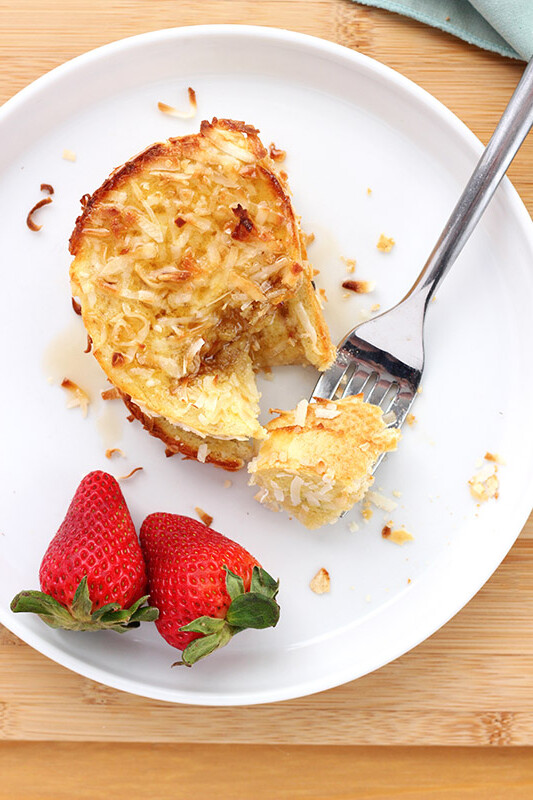 White plate with a piece of french toast and a fork with a bite on it