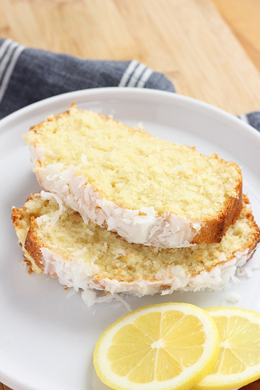 slices of coconut bread on a white plate with fresh lemon slices