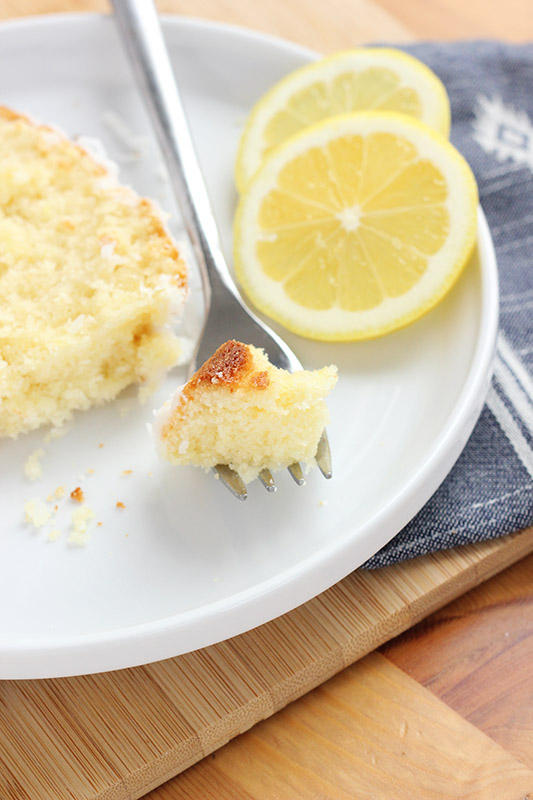 Bite of lemon loaf on a white plate with a fork