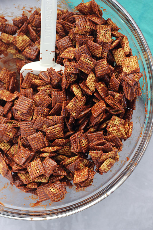 chex cereal covered in chocolate with a glass bowl