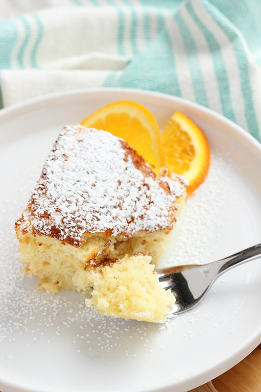 orange cake with a bite on a fork sitting on a white plate