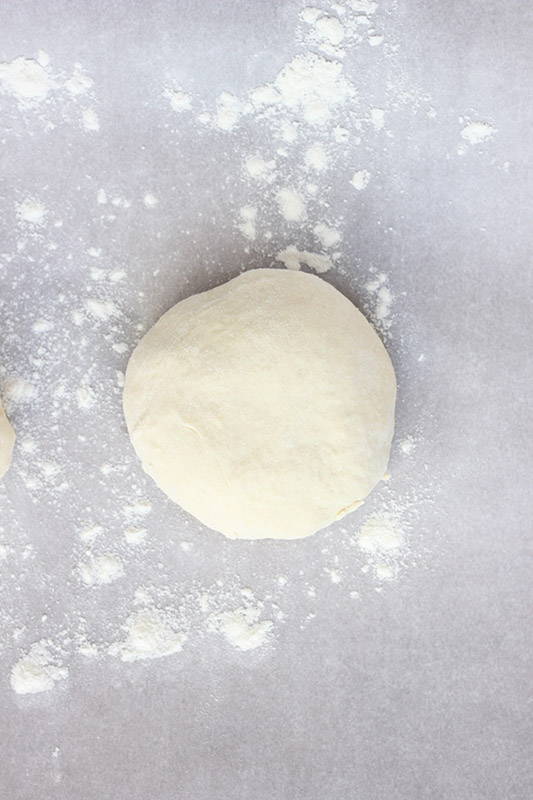 round pizza dough on a piece of parchment paper