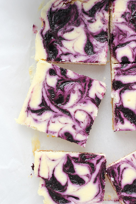 cheesecake bars sliced and placed on a piece of parchment