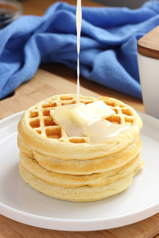 syrup being drizzled onto waffles