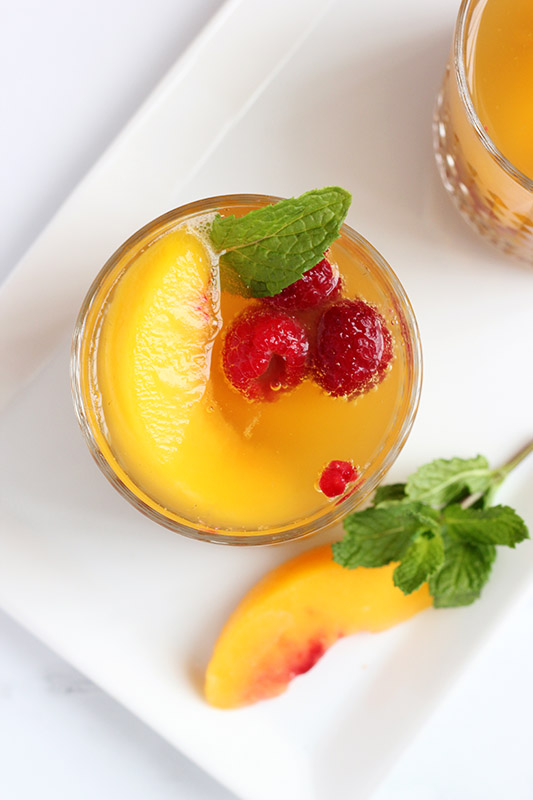 top down image of a cocktail filled with fresh raspberries and peaches