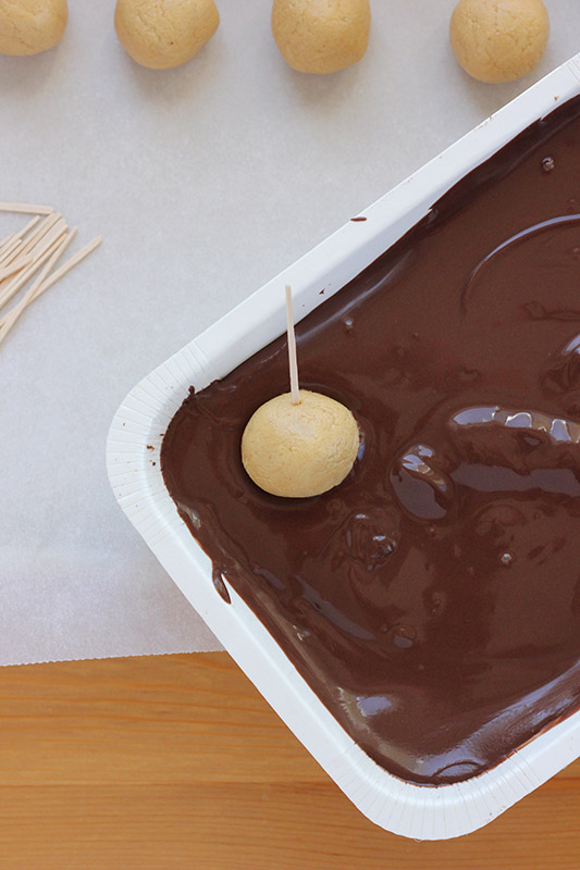 Peanut butter ball being dipped into melted chocolate
