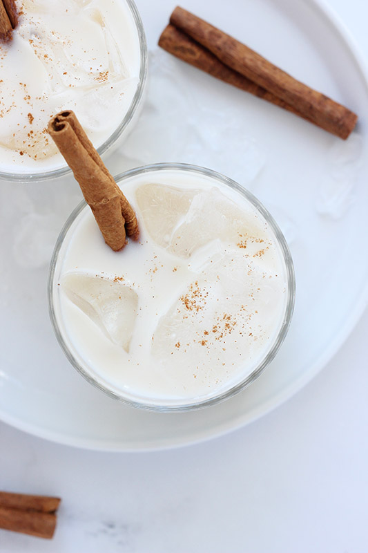 top down image of a glass of horchata dusted with cinnamon and a cinnamon stick