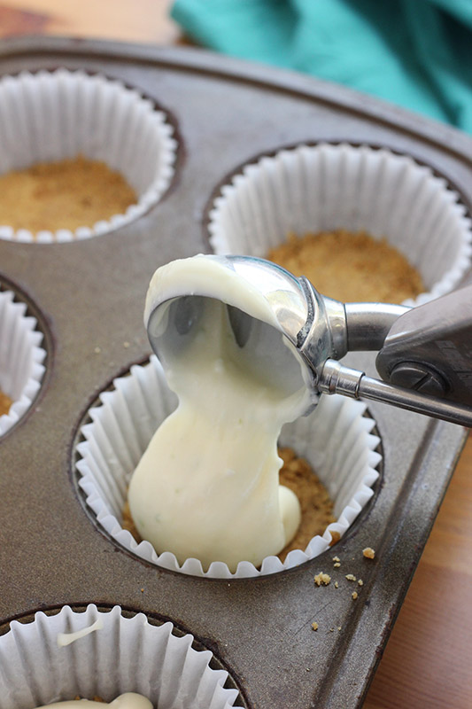 scoop of cheesecake batter being spooned into cupcake liners