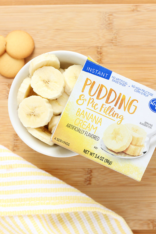 Banana Cream Pudding box balancing on a white bowl of sliced bananas 