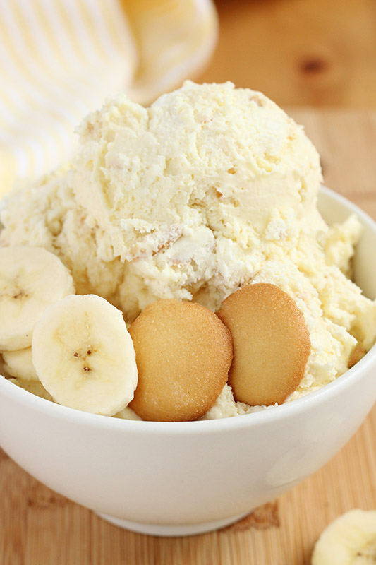 close up image of ice cream scoops inside a white bowl with fresh banana slices and two vanilla wafer cookies